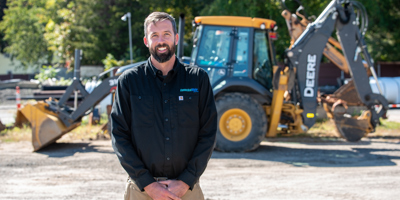 CT Water employee standing in front of a backhoe